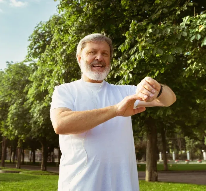 An older man in a park checking his watch (brand artwork)